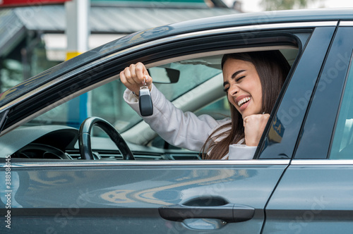 Young woman successfully passed a driving school test, holding keys of her first car