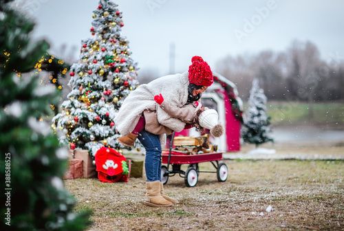 Asian woman holding her little daughter against Christmas outdoor background.  photo