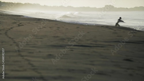 Surfer running towards ocean to enter water and catch some epic waves, slowmo