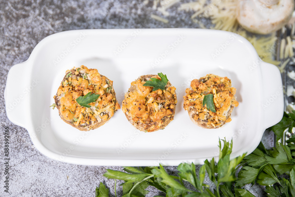 Baked stuffed mushrooms on white plate with shredded parmesan & parsley garnish Baked stuffed mushrooms on white plate with shredded parmesan & parsley garnish