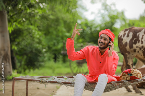 Young Indian farmer talking on mobile phone and showing happy expression photo