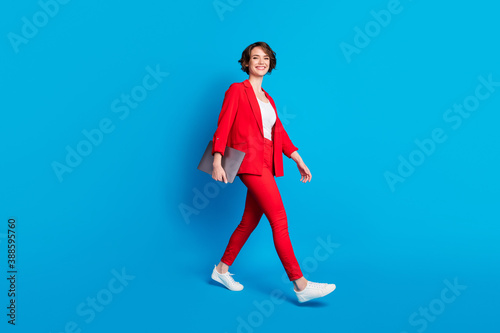 Full length body size view of attractive cheerful businesslady specialist going carrying laptop isolated over bright blue color background © deagreez