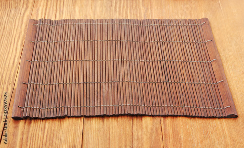 Brown bamboo food placemat on wooden table taken closeup. photo