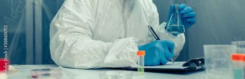 Female scientist with bacteriological protection suit investigating in the laboratory