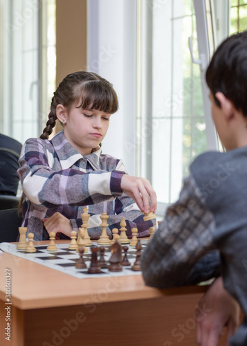 The girl at the chessboard. Competition. Chess tournament. The girl plays chess. The girl against the boy plays chess. Game of chess. Portrait