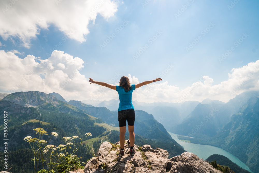 Girl standing on the top of a cliff watching a beautiful mountain scenery in the bavarian Alps