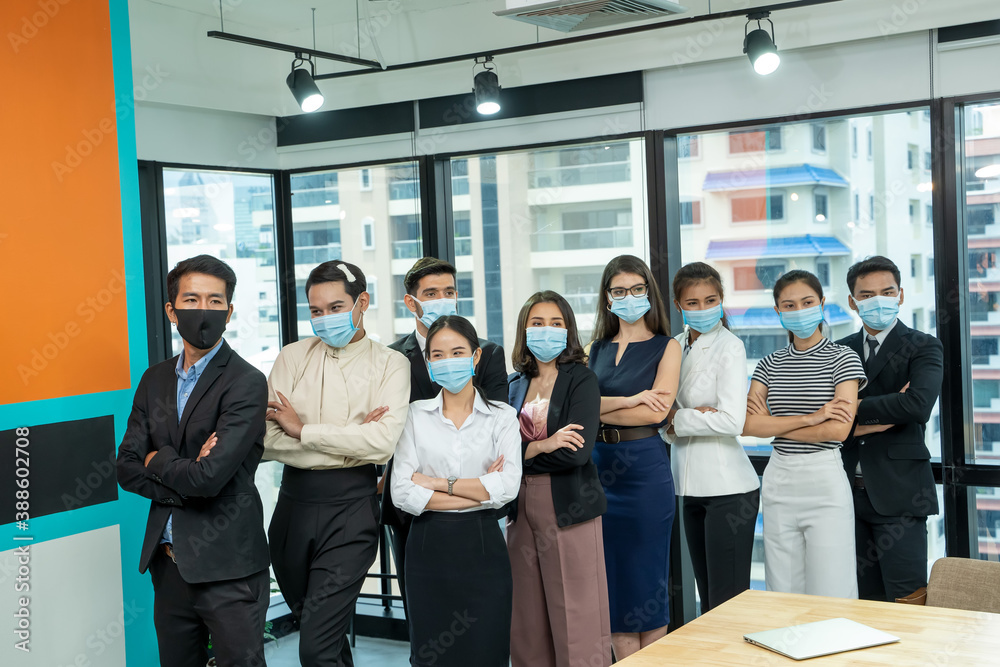 Diverse business people group with face mask protect from Corona virus standing together as team in office,Support and collaboration together to overcome pandemic of Corona virus to reopen business. Diverse business people group with face mask protect from Corona virus standing together as team in office,Support and collaboration together to overcome pandemic of Corona virus to reopen business.