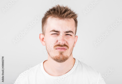 Unsatisfied sleepy guy with messy hair and gloomy smile, standing over gray background.