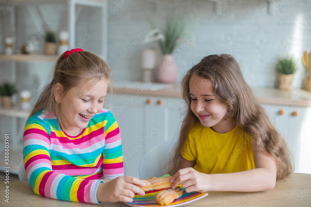 Fototapeta premium Teen girls together play and eat cakes in the kitchen. Happy kids concept