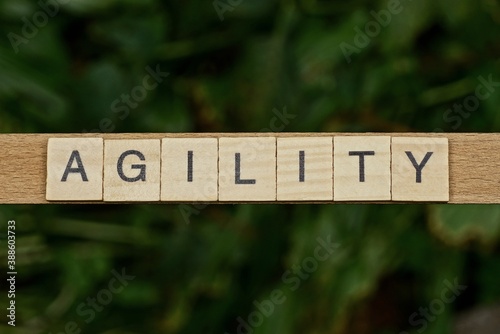 gray word agility made of wooden square letters on green background photo