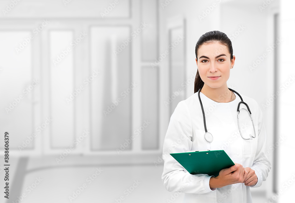 Portrait of attractive female doctor with stethoscope standing at hospital corridor Portrait of attractive female doctor with stethoscope standing at hospital corridor