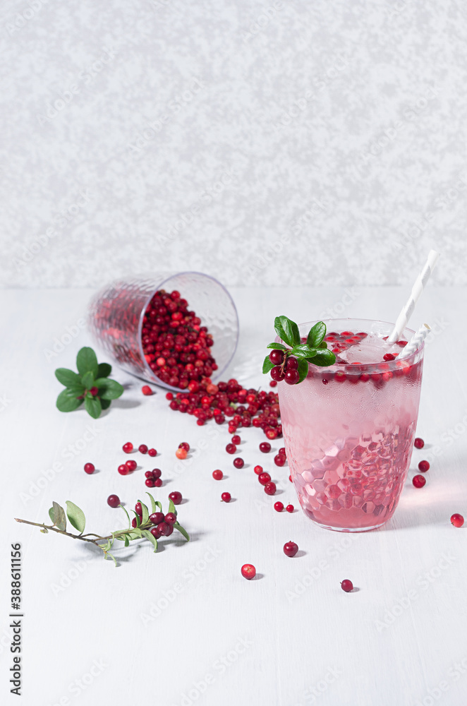 Sour pink cocktail of lingonberry with red berry, ice cubes and straws on white wood board, copy space, top view. Sour pink cocktail of lingonberry with red berry, ice cubes and straws on white wood board, copy space, top view.