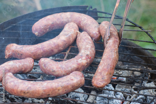 Pork sausages are grilled during a picnic in outdoors.