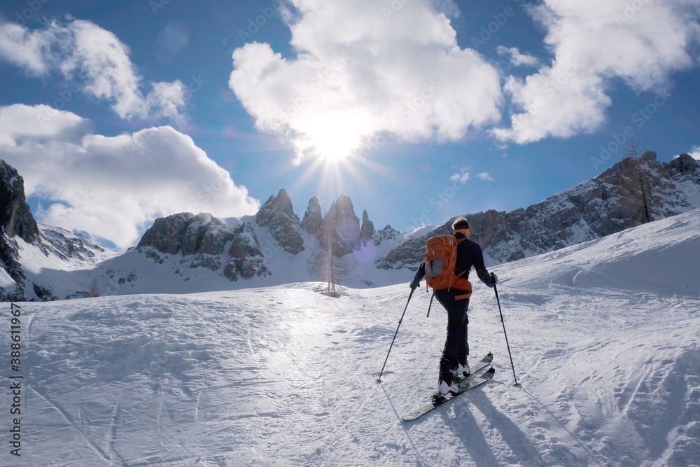 Skier during ski touring, climbing in mountains on sunny day. Tre Cime Park, Dolomites, Italy