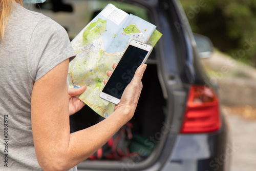 woman traveling by car with mobile phone and map