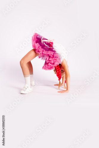 Wallpaper Mural portrait of a cute girl in bright multicolored clothes and with colored braids and in a skirt shows dance exercises on a white background Torontodigital.ca