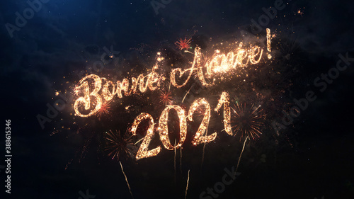 2021 Happy New Year greeting text in French with particles and sparks on black night sky with colored fireworks on background, beautiful typography magic design.