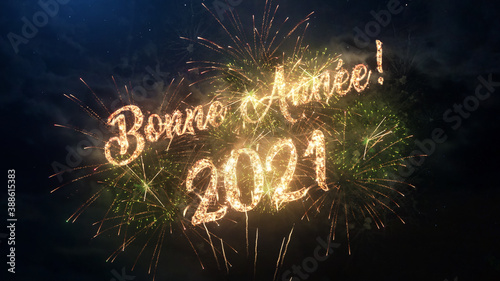 2021 Happy New Year greeting text in French with particles and sparks on black night sky with colored fireworks on background, beautiful typography magic design.