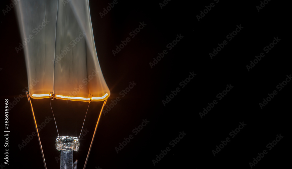 Filament light bulb on fire and smoking, isolated black background. Copy space for text. Filament light bulb on fire and smoking, isolated black background. Copy space for text.