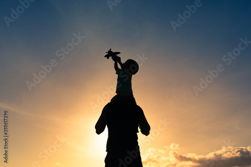 Silhouette of father son int the sunset playing with toy airplane. Family freedom  and inspiration concept. 