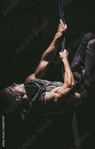 Athlete with a well-developed musculature lifts up his body on the rope.
