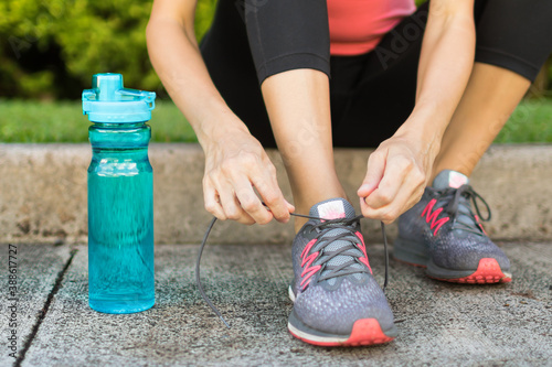 Female getting ready to go on a run next to bottle of water. Health active lifestyle concept. 