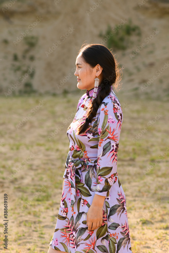 Mongolian woman wears the national costume in a desert at sunset. Mongolian woman wears the national costume in a desert at sunset.