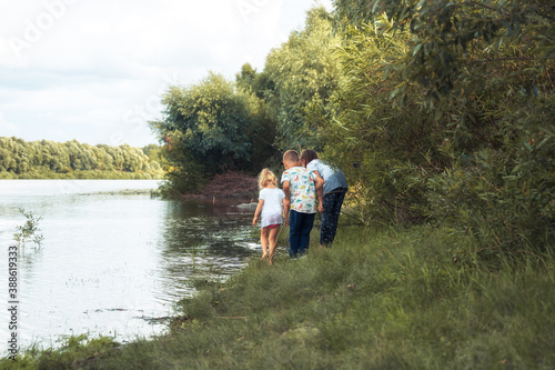 Curious children friends walking together in countryside on river bank and looking for something concept children curiosity and happy childhood