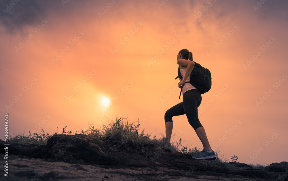 silhouette of a person hiking up mountain at sunrise
