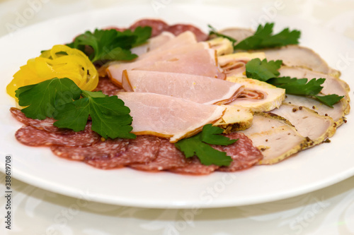 Slicing Sausage and ham on a plate. Cold food appetizer on the table.