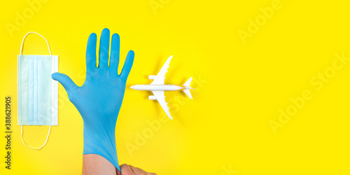Plane model and face medical mask on a yellow background . Doctor hand with glove