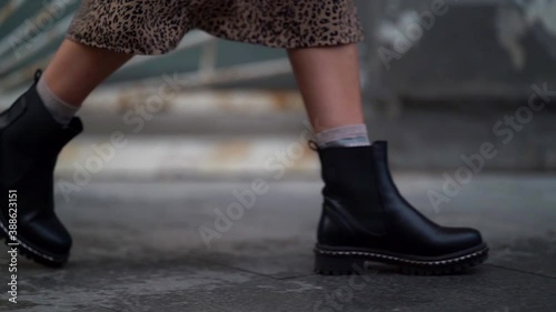 casual style shoes on woman feet, lady is walking at autumn day in city, closeup view on feet