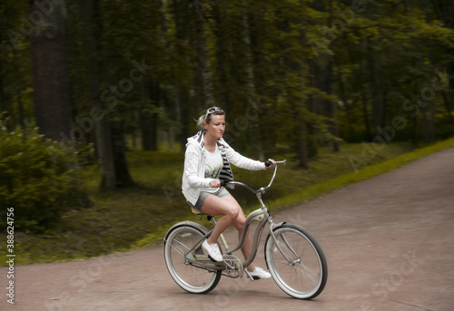 Woman rides a bicycle along the alleys of a summer park