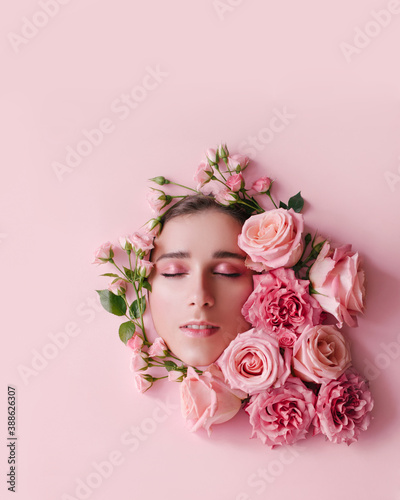 Fototapeta Naklejka Na Ścianę i Meble -  Close up portrait of beautiful woman face wih perfect skin posing with roses on pink background.