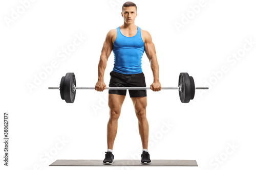 Full length portrait of a bodybuilder in sportswear lifting weights and looking at camera
