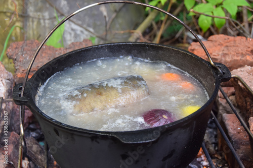 fish soup with onions and carrots on the fire in a cauldron