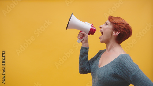 redhead woman in 40s speaking in loudspeaker. High quality photo