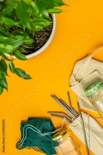 Zero waste concept. Cotton bag, bamboo cutlery, glass jar, and straws on yellow background, flat lay, copy space. Plastic free