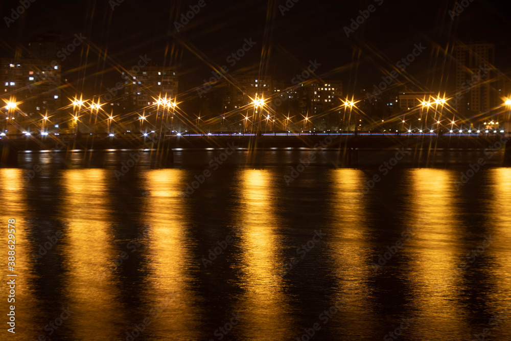 Night city view of the old bridge across the river lanterns six-pointed stars with water reflections