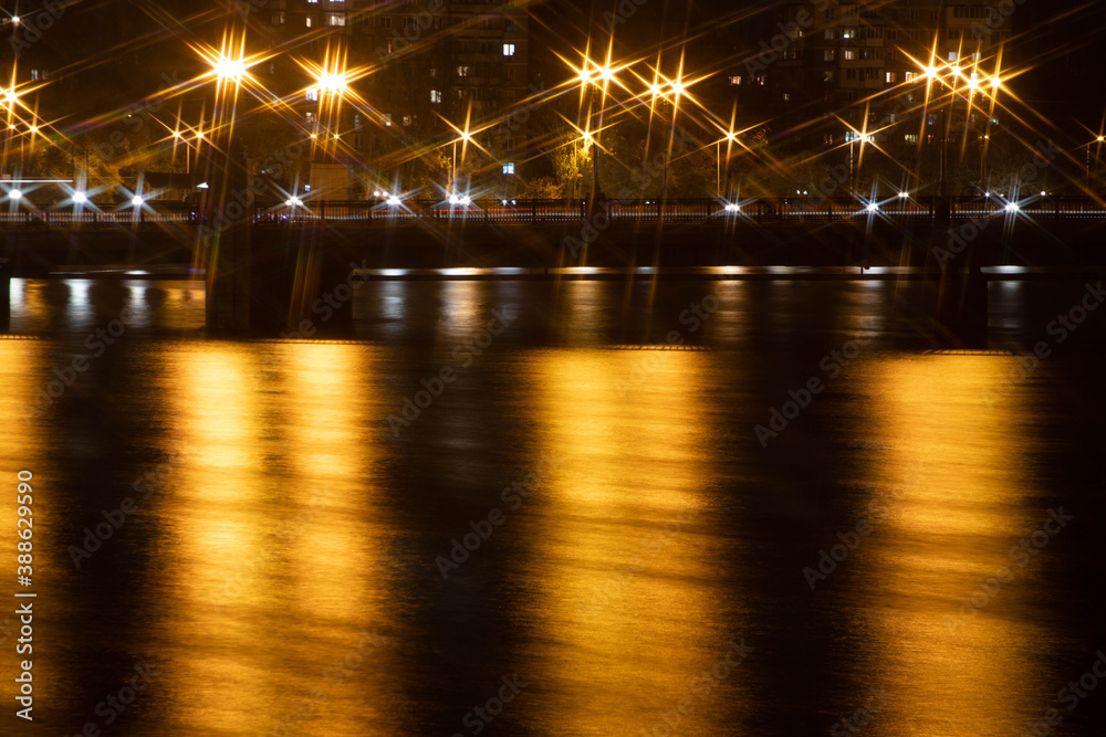 Night city view of the old bridge across the river lanterns six-pointed stars with smooth water reflections