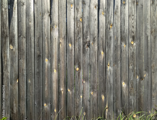 background old grunge wooden fence made of gray-brown boards in bright sunbeams