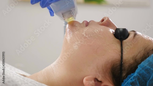 Nonsurgical facelift in beauty salon. machine cosmetology. Facelift device makes flashes. Faceskin renovation. Close-up shot of woman in protective glasses getting beauty procedure. 4 k photo