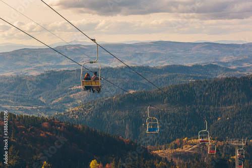 landscape photography, autumn forest and mountains, sunny day ski lift lifts people up the mountain