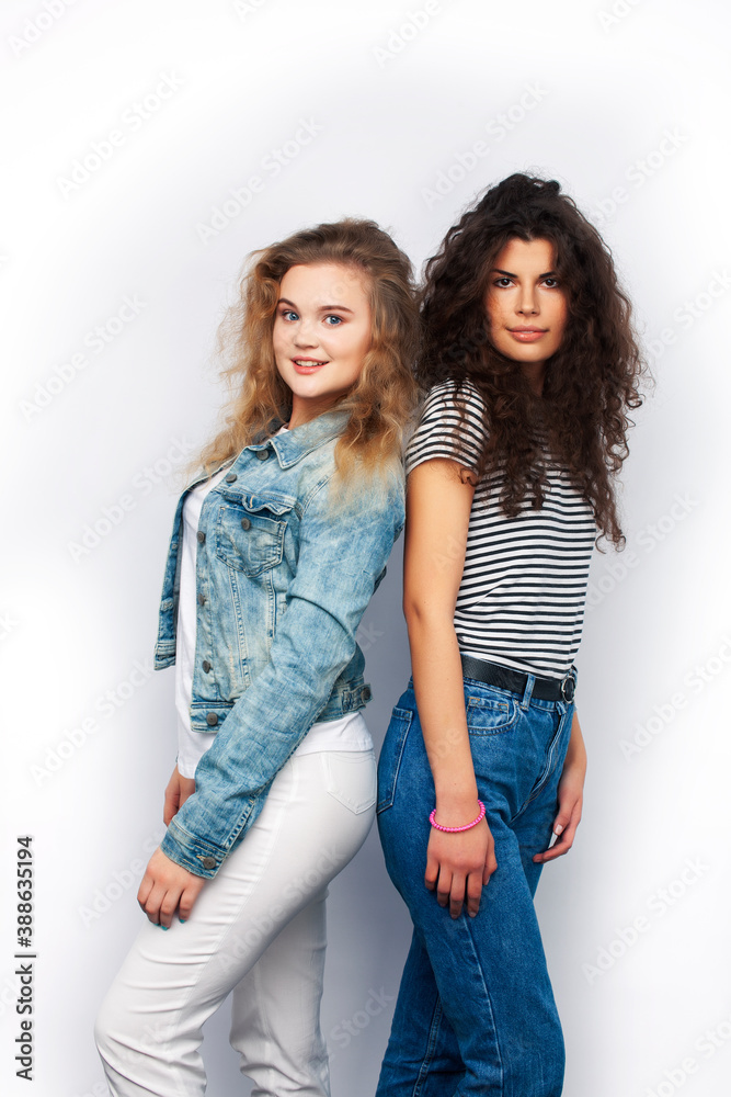 young pretty teenage girls friends with blond and brunette curly hairs posing cheerful isolated on white background, lifestyle people concept young pretty teenage girls friends with blond and brunette curly hairs posing cheerful isolated on white background, lifestyle people concept