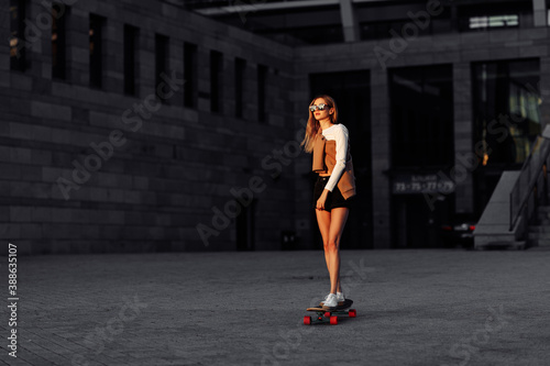 Young woman rides a longboard around the city.