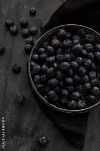 Overhead view of a cooling rack full of delicious blueberries inside on a wooden background. Image focused on the top of the pile of blueberries.