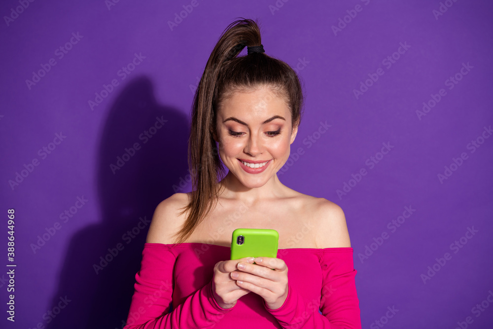 Photo of pretty young lady hands hold mobile phone toothy smile excited wear pink unclothed shoulders top isolated purple color background Photo of pretty young lady hands hold mobile phone toothy smile excited wear pink unclothed shoulders top isolated purple color background