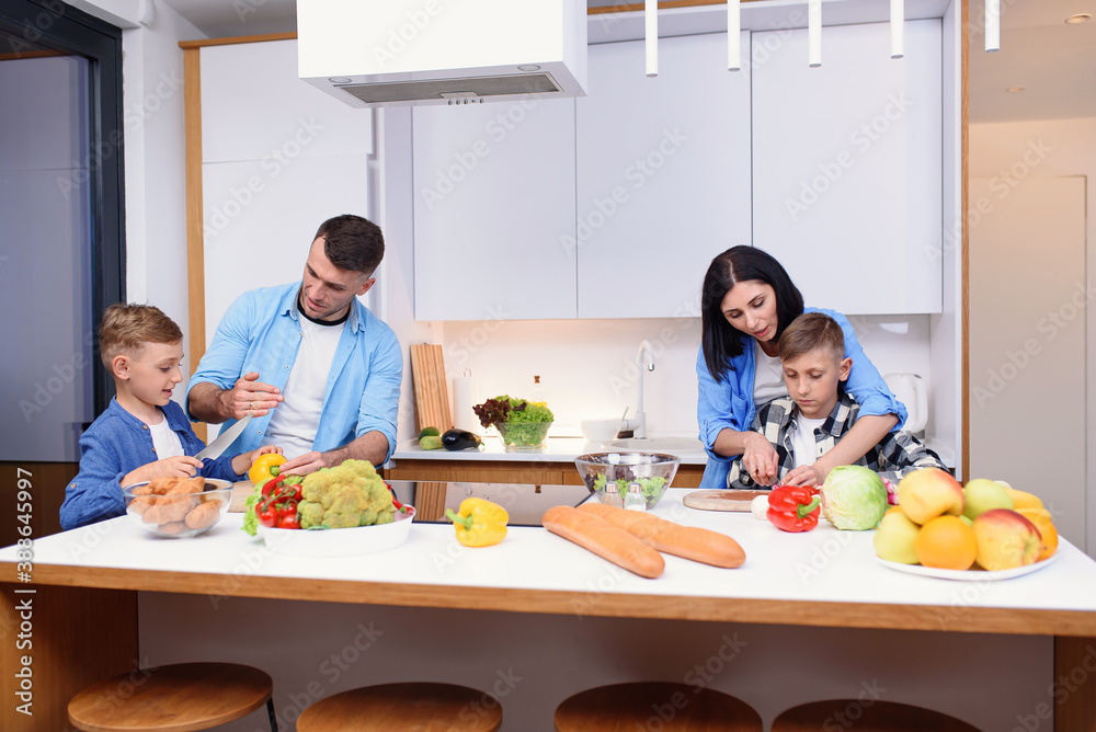 Stylish young family with two sons preparing healthy vegetarian breakfast with fresh vegetables on cozy home kitchen.