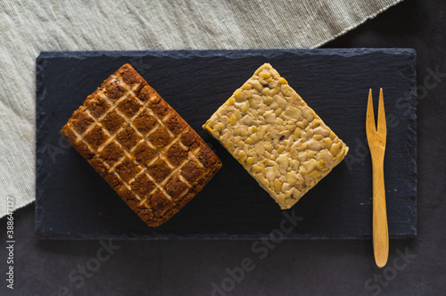 Top view of two pieces of soy products. Smoked tofu and tempeh. Healthy protein foods on a slate board