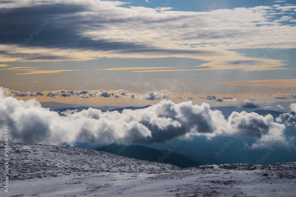 Obraz premium Dramatic sky with colorful sunset on top of snowy mountain, seeing other mountains in gradient through clouds, Serra da Estrela Natural Park PORTUGAL